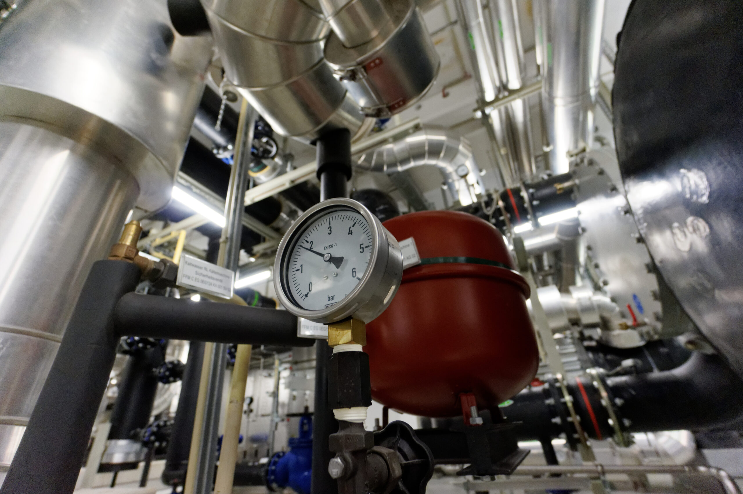 Pressure Guage v priemyselnom prostredí s potrubiami a zariadeniami.